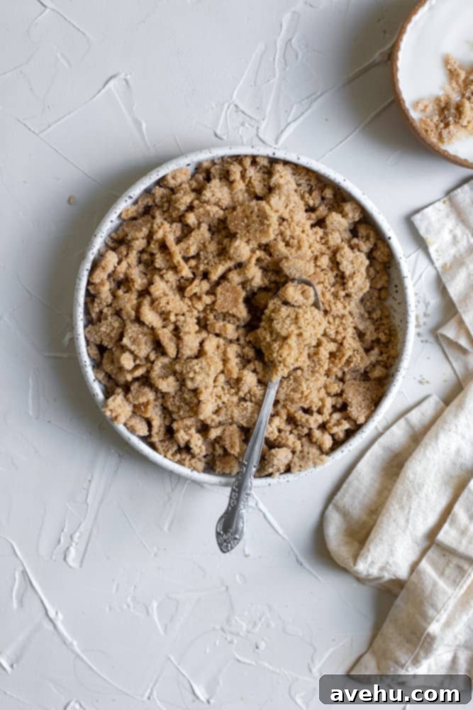 Easy Classic Streusel Crumbs Nut and Oat Free 2 Freshly made streusel crumb topping in a white ceramic bowl with a spoon, ready to be used on baked goods