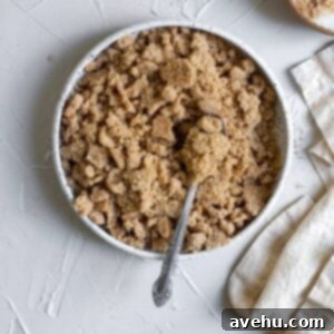 Easy Classic Streusel Crumbs Nut and Oat Free 8 Streusel in a white ceramic bowl with a spoon on a white surface, showcasing the delicious crumbly texture