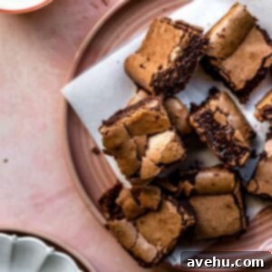 Stack of rich, fudgy one-bowl brownies with crinkly tops on a vibrant pink plate