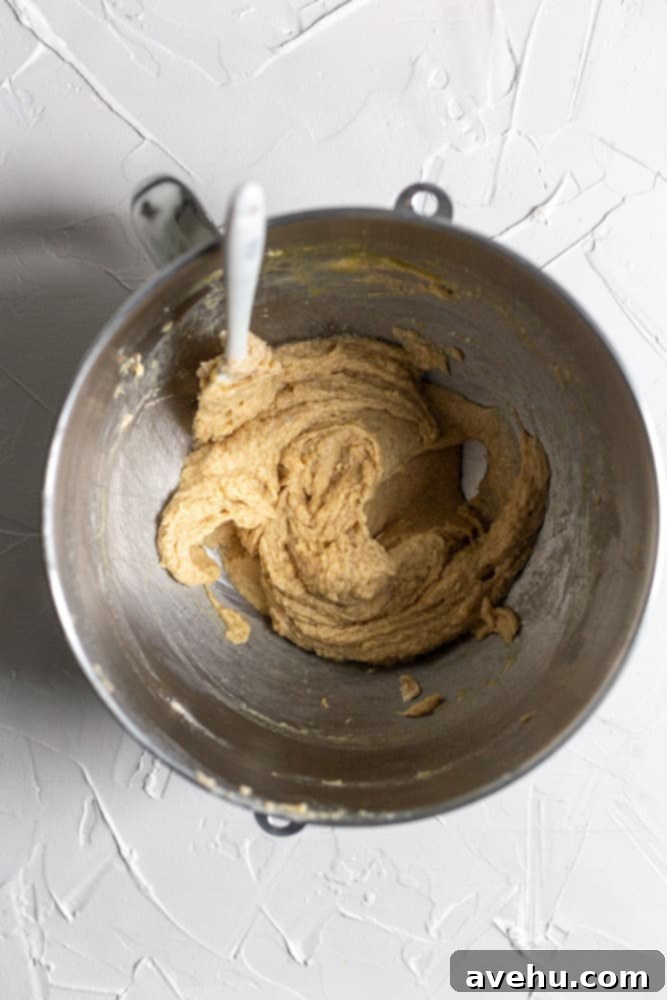 Golden Coconut Delights 2 Cookie batter being creamed in a stand mixer bowl on a white surface.