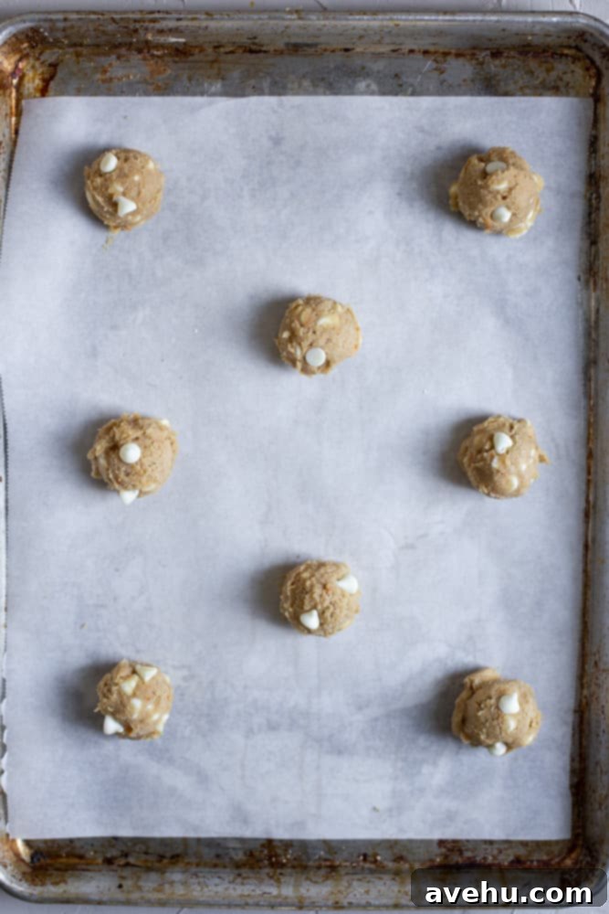 Zesty Orange Crunch-Chews 6 Orange cookie dough balls scooped onto a parchment-lined baking sheet, ready for chilling.