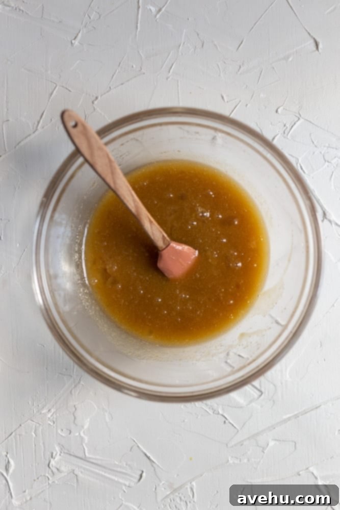 Ultimate Gooey Skillet Chocolate Chip Cookie 5 melted butter and sugar mixed in a glass bowl, showcasing the initial wet ingredients