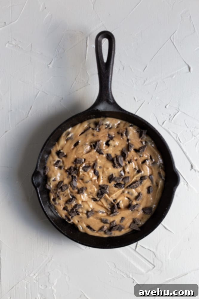 Ultimate Gooey Skillet Chocolate Chip Cookie 7 Cookie batter evenly spread in a cast iron skillet, ready for baking