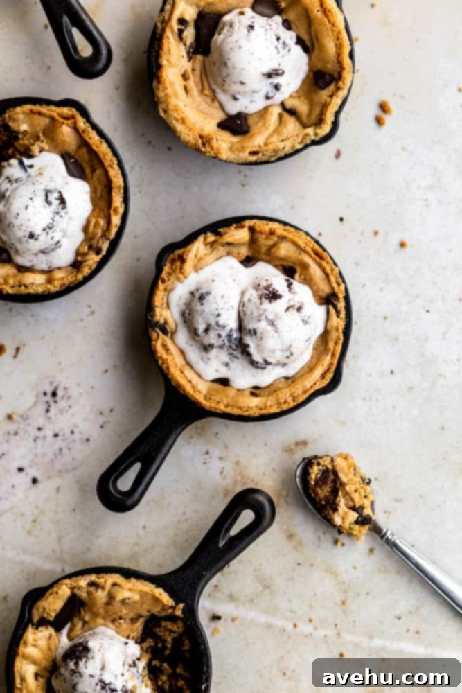 Ultimate Gooey Skillet Chocolate Chip Cookie 8 Mini skillet chocolate chip cookies on a beige surface, each topped with ice cream