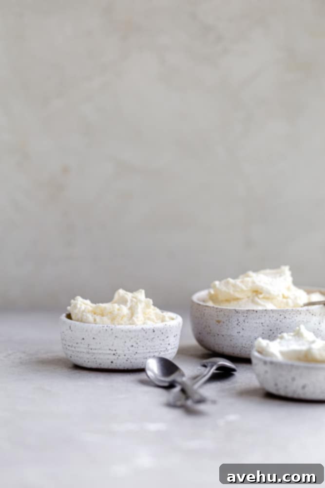 Indulgent Mascarpone Frosting: 10-Minute Perfection 6 Three small, elegant bowls filled with whipped mascarpone frosting, artfully placed on a textured gray surface, showcasing the versatility and beautiful presentation of this delicious dessert topping.