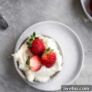 Indulgent Mascarpone Frosting: 10-Minute Perfection 7 A bowl of creamy mascarpone frosting, topped with vibrant red strawberries, sits on a white plate. This image captures the rich texture and inviting presentation of the 10-minute whipped mascarpone frosting, ready for any dessert.