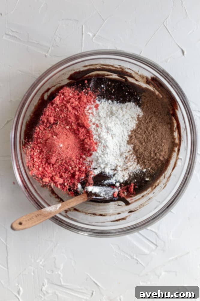 Quick Strawberry Fudge Brownies 5 Dry ingredients for strawberry brownies, including ground freeze-dried strawberries, flour, and cocoa, being mixed in a large glass bowl