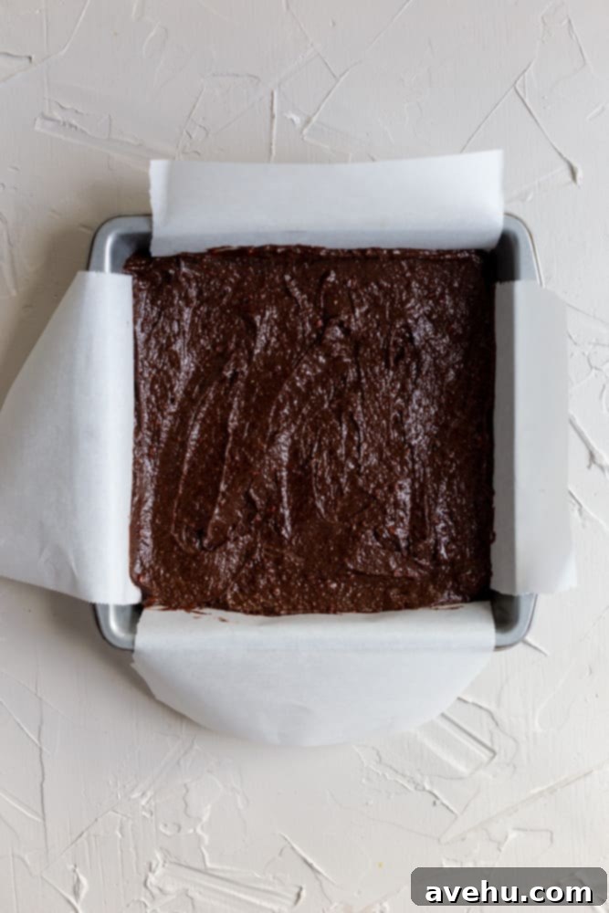 Quick Strawberry Fudge Brownies 6 Rich, fudgy strawberry brownie batter evenly spread in a baking pan lined with parchment paper, ready for the oven