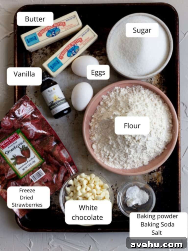 Decadent Strawberry Chewies 3 A collection of ingredients for making strawberry cookies, including butter, sugar, flour, eggs, freeze-dried strawberries, and white chocolate chips, neatly arranged on a kitchen counter.