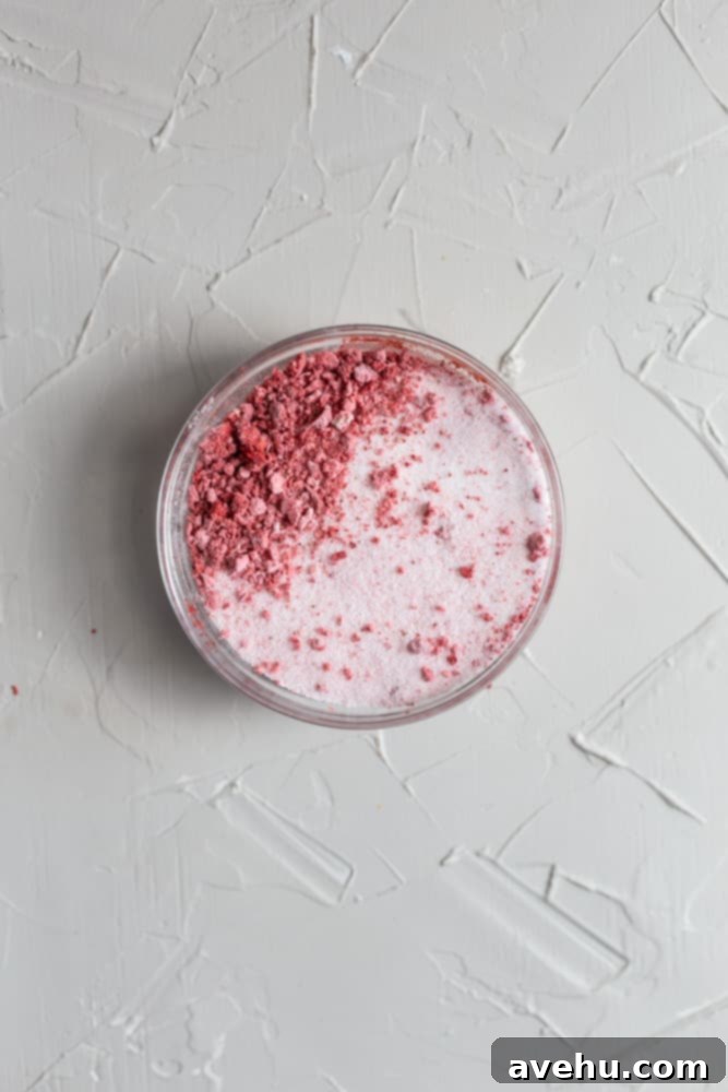 Decadent Strawberry Chewies 10 A small glass bowl holding a mixture of granulated sugar and pulverized freeze-dried strawberries, displaying a lovely pink hue.