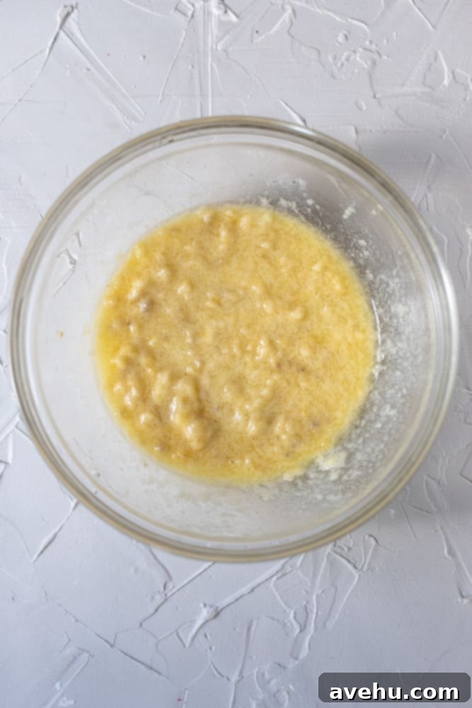 Simple and Scrumptious Banana Chocolate Chip Muffins 4 Wet banana muffin batter in a glass bowl, showcasing the mashed bananas and liquid ingredients.