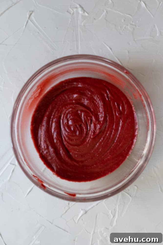 Simply Decadent Red Velvet Brownies 4 red velvet brownie batter in a glass bowl on a light gray surface, showing its vibrant red color