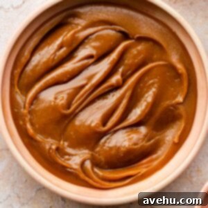 A charming pink bowl filled with rich, homemade bourbon caramel sauce, ready to be enjoyed or drizzled over desserts.