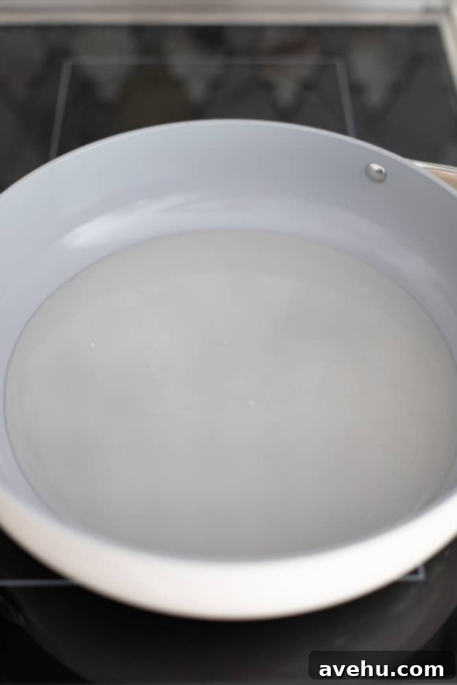 Foolproof Bourbon Caramel Sauce Visual Guide 4 Granulated sugar and water perfectly combined in a light gray, heavy-bottomed pot, ready to be heated and transformed into caramel.