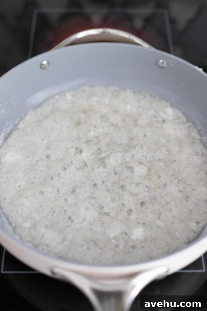 Foolproof Bourbon Caramel Sauce Visual Guide 7 More distinct sugar clumps and larger clusters forming within the bubbling caramel mixture, a common and expected stage during caramelization.