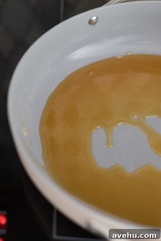 Foolproof Bourbon Caramel Sauce Visual Guide 8 The caramel mixture has reached a rich, smooth amber color, with all sugar clumps melted and fully caramelized, signifying the perfect stage for adding dairy.