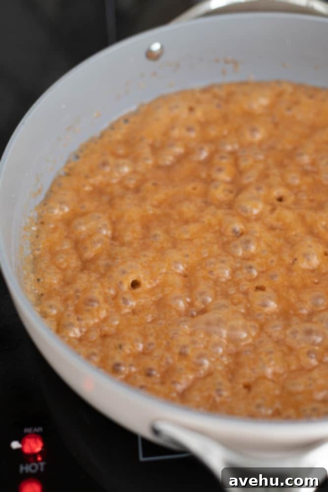 Foolproof Bourbon Caramel Sauce Visual Guide 9 The bourbon caramel sauce actively bubbling in the light gray pot after all ingredients have been added, showcasing its smooth and vibrant texture.