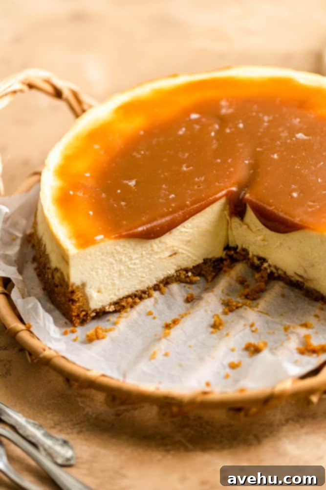 Salted Caramel Cheesecake 2 A perfectly sliced salted caramel cheesecake, with golden caramel sauce generously drizzled over a creamy filling, resting on a rustic wooden tray. A piece has been removed, revealing its delicious layers.