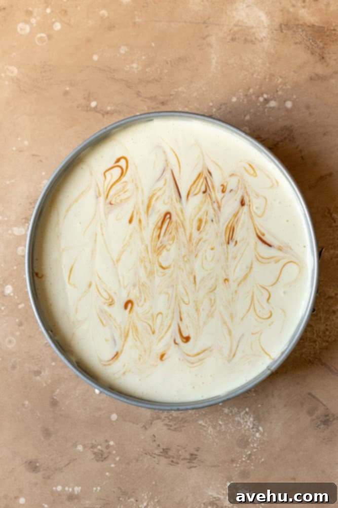 Salted Caramel Cheesecake 8 Cheesecake batter in a springform pan with caramel sauce elegantly swirled through it, creating a beautiful marbled effect.