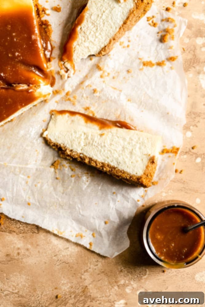 Salted Caramel Cheesecake 10 A delectable slice of salted caramel cheesecake lying on its side on parchment paper, with a jar of rich caramel sauce in the background.
