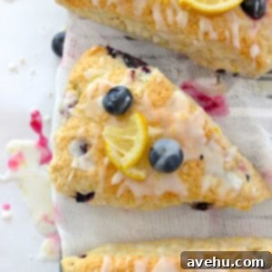 Effortless Blueberry Lemon Scones 2 Closeup of perfectly baked blueberry lemon scones, glistening with lemon glaze, resting on cheesecloth.