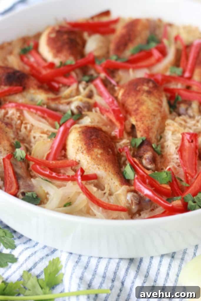 Simple and Savory Arroz Con Pollo 3 Close-up of baked Arroz con Pollo in a white pan, showcasing crispy chicken skin and vibrant vegetables