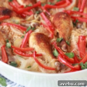 Simple and Savory Arroz Con Pollo 5 A vibrant, easy one-pan Arroz con Pollo in a white dish, garnished and served on a rustic wooden table.