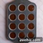 A muffin tin lined with chocolate cupcake batter