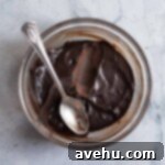 Hardened chocolate ganache ready to fill cupcakes in a glass bowl with spoon