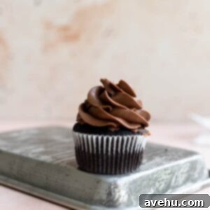 A chocolate cupcake with piped chocolate buttercream on a turned over metal tray.