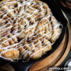 Flaky Cinnamon Swirls 2 A closeup of cinnamon buns made out of phyllo dough with a cream cheese glaze in a cast iron skillet, showing crispy layers.