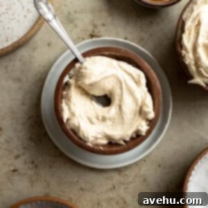 Caramel buttercream swirled in a wooden bowl with a spoon sticking out