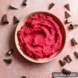 Speedy Raspberry Buttercream Bliss 2 Bright pink raspberry frosting in a bowl on a pink surface surrounded by piping tips