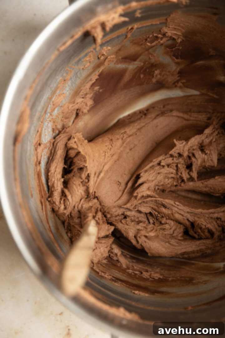 5-Minute Cocoa Chocolate Buttercream Frosting 6 Lush, glossy chocolate buttercream frosting swirled in a mixing bowl, showcasing its smooth and fluffy texture, ready for decorating.