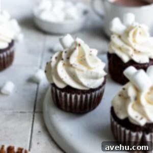 Hot chocolate cupcakes on a white plate with hot cocoa in the background.