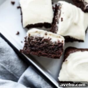 Tangy Cream Cheese Fudgy Brownies 2 A brownie with cream cheese frosting on its side in a white pan, showcasing its layers.