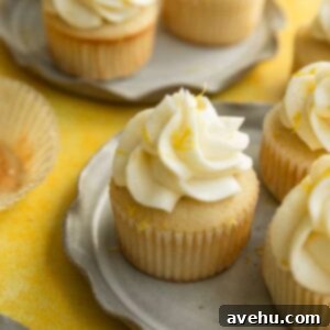 Effortless Lemon Sunshine Cupcakes 2 A lemon cupcake with frosting and lemon zest sitting on a gray ruffled plate.