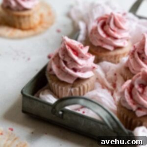 Luscious Strawberry Delights 2 Strawberry cupcakes sitting in a green tray on a gray surface.