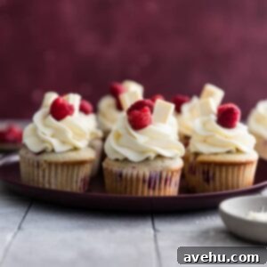 Decadent White Chocolate Raspberry Cupcakes 2 White chocolate raspberry cupcakes on a maroon plate.