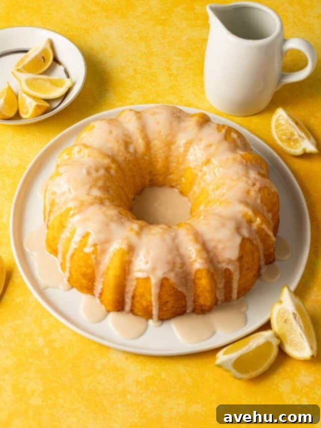 Quick & Moist Lemon Bundt Cake 2 A vibrant lemon pudding bundt cake, topped with a tangy lemon glaze, rests on a pristine white plate atop a cheerful yellow surface, ready to be enjoyed.