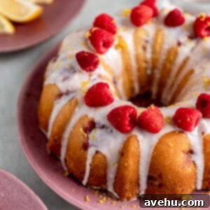 Sunshine Berry Buttermilk Bundt 2 A closeup of a lemon raspberry bundt cake garnished with white glaze, raspberries, and lemon zest.