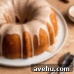 The smooth cinnamon glaze being drizzled artfully over the cooled bundt cake, creating beautiful drips.