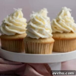 Coconut cupcakes on a white cake stand on a pink backdrop.