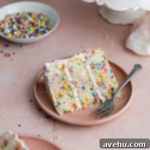 Artisan Confetti Cake 2 A vibrant slice of homemade confetti cake with funfetti frosting on a pink plate, garnished with extra sprinkles.