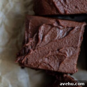 A brownie topped with frosting on a brown piece of parchment paper.