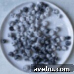 Pillowy Soft Blueberry Cupcakes 5 Blueberries dusted with flour on a white plate.