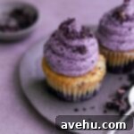 Pillowy Soft Blueberry Cupcakes 7 Two blueberry cupcakes on a plate on a purple surface.