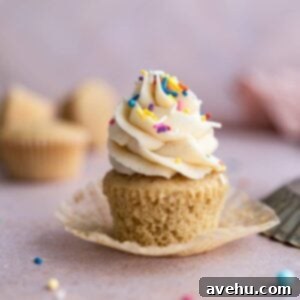 Effortless Oat Milk Vanilla Cupcakes 2 An unwrapped vanilla dairy free cupcake with sprinkles on top.