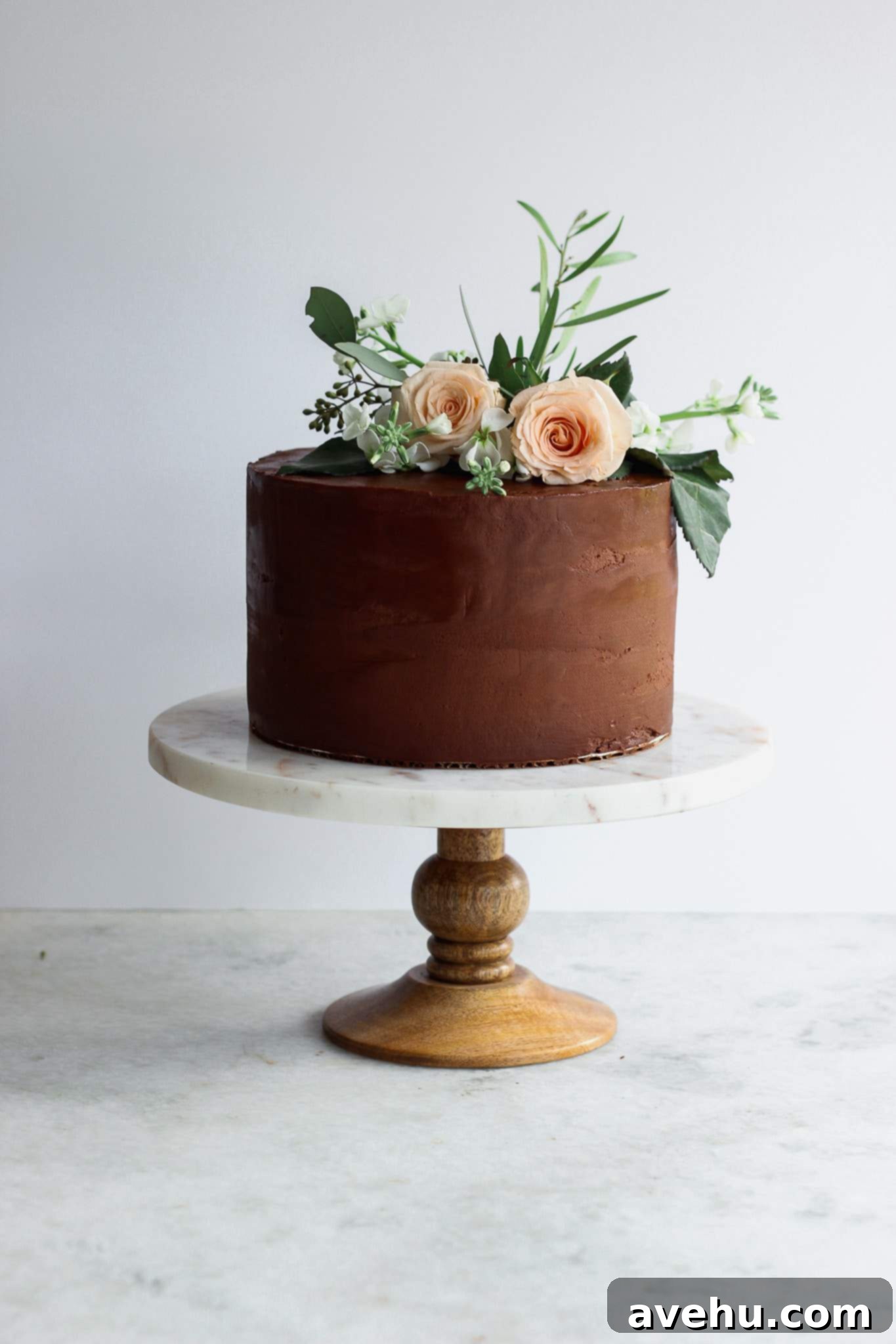 Elevate Your Cakes To Pro Level: 10 Essential Techniques 12 A chocolate cake on a marble and wood cake stand with flower decorations
