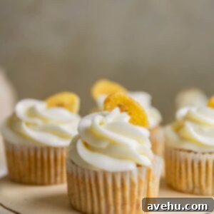 Pure Banana Indulgence Cupcakes 2 A closeup of a banana cupcake frosted with cream cheese frosting and garnished with a banana chip.